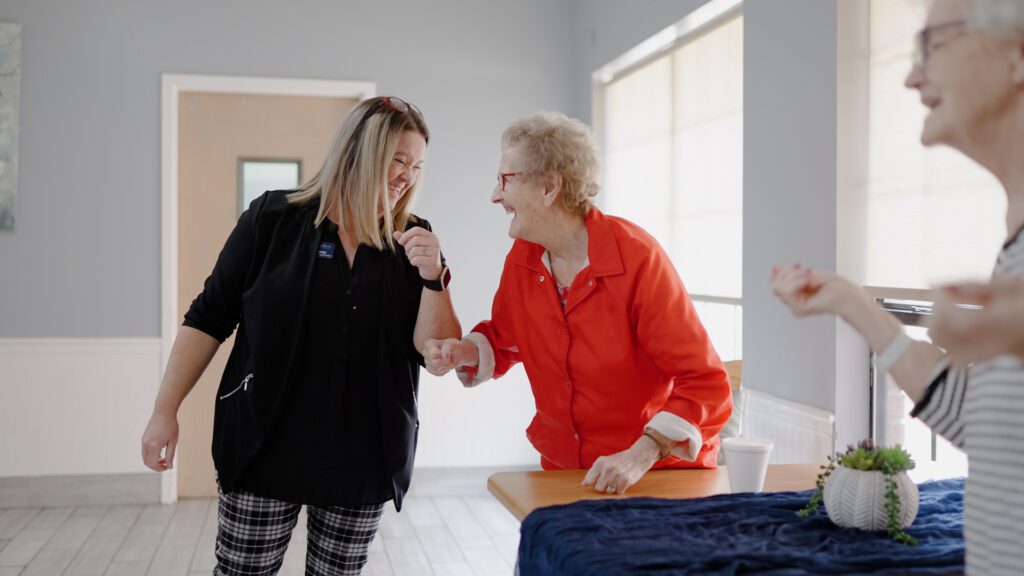 A nurse smiles at a resident of a long term care facility
